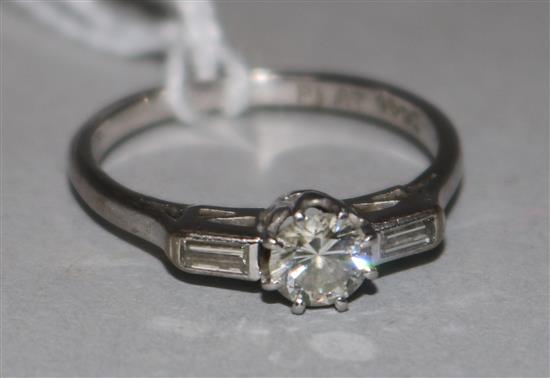 An 18ct white gold and platinum single stone diamond ring with baguette cut diamond set shoulders, size K.